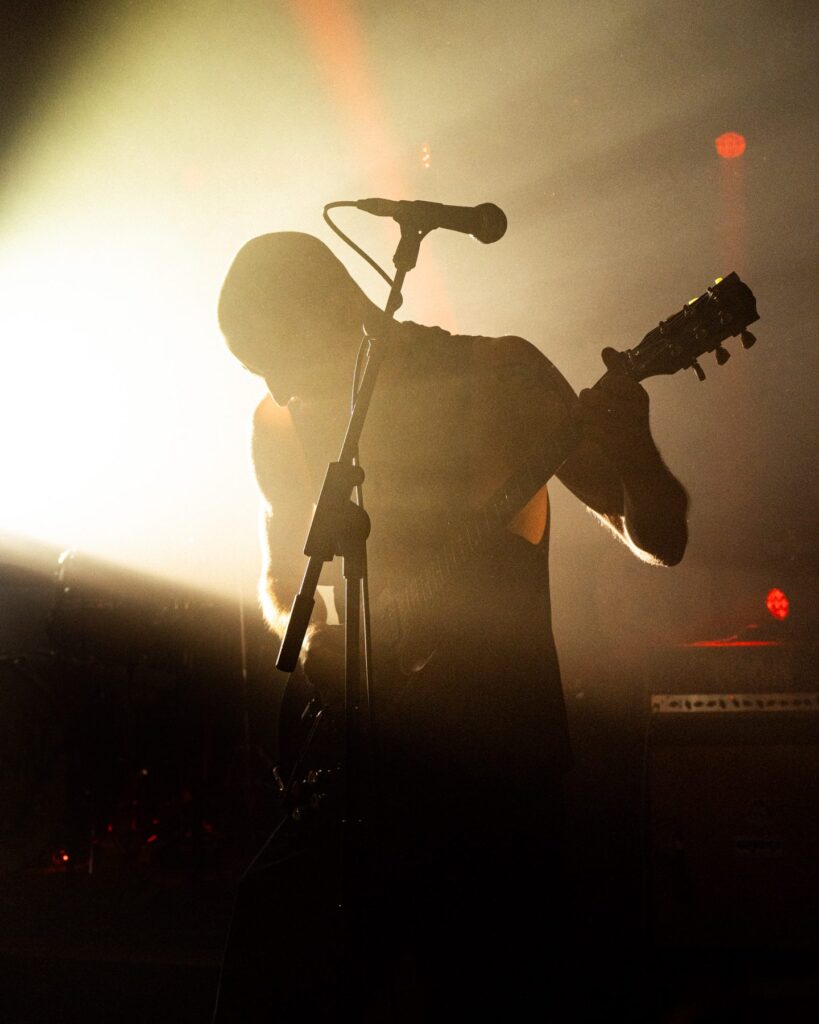 Guitarist backlit in haze during a live performance at The Shrine