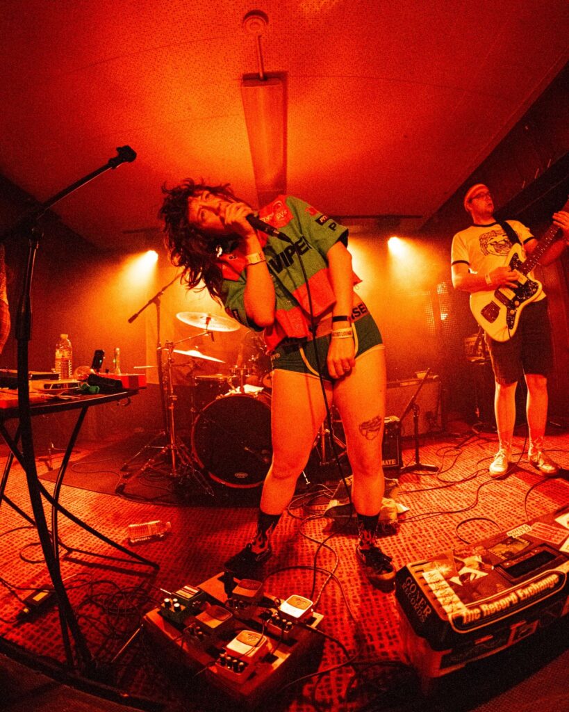 Singer performing in a red-lit room during a live set at Treefort Music Hall